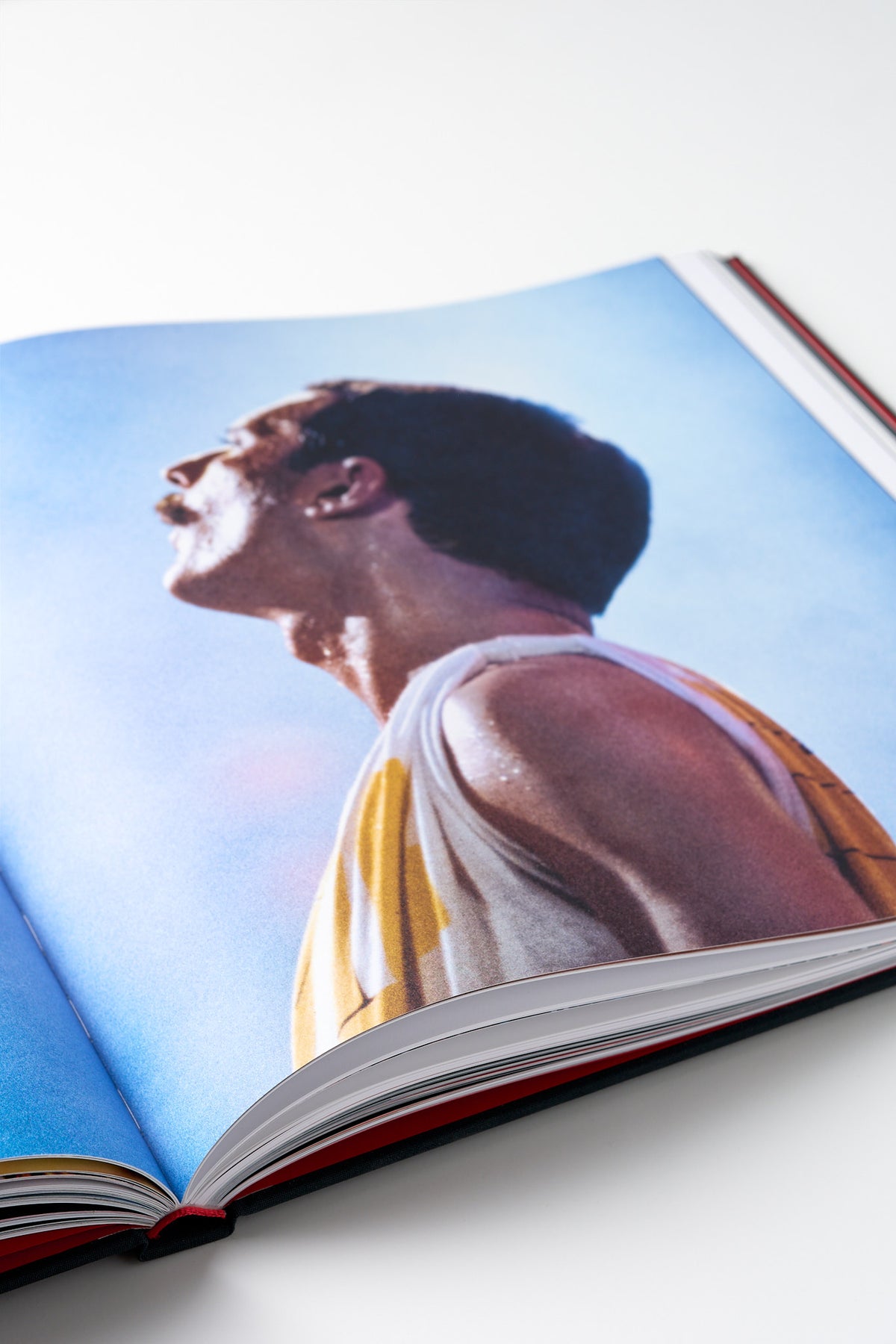 Otevřená kniha s fotografií Freddieho Mercuryho na pódiu